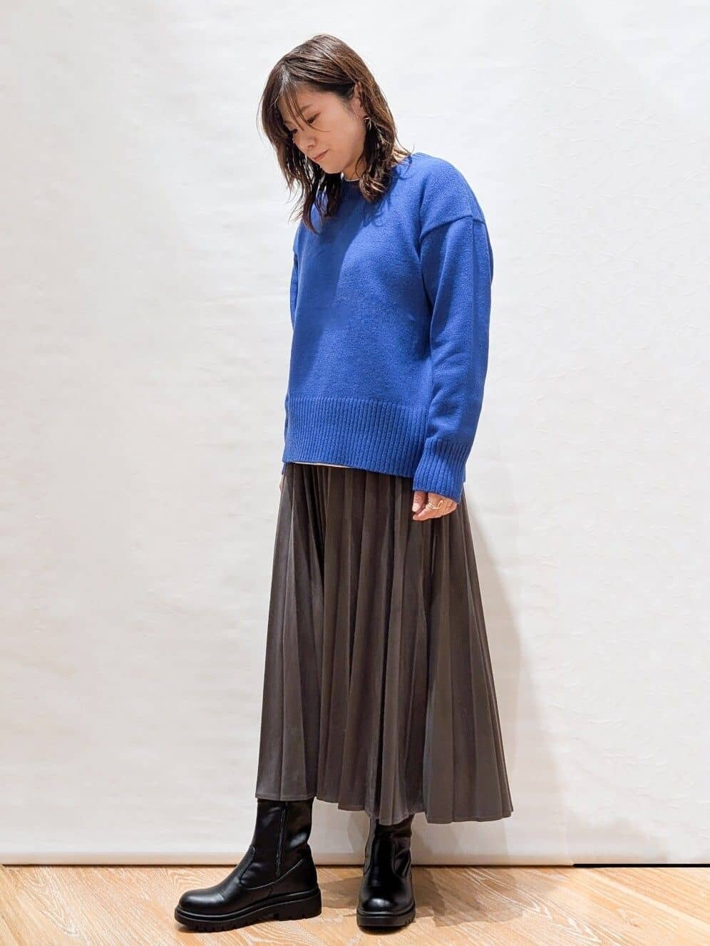ホワイト系のTシャツ/カットソー、ブルー系のニット/セーター、グレー系のスカートを着用したレディースの秋コーディネートの4枚目の写真