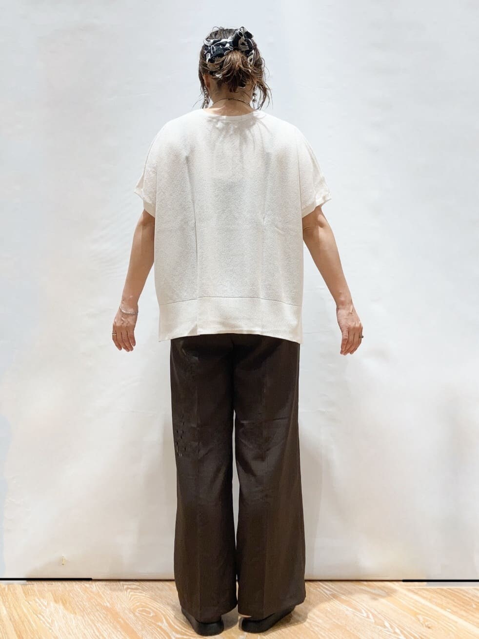 ホワイト系のニット/セーター、ブラウン系のその他パンツ、ブラック系のトートバッグを着用したレディースの夏コーディネートの5枚目の写真