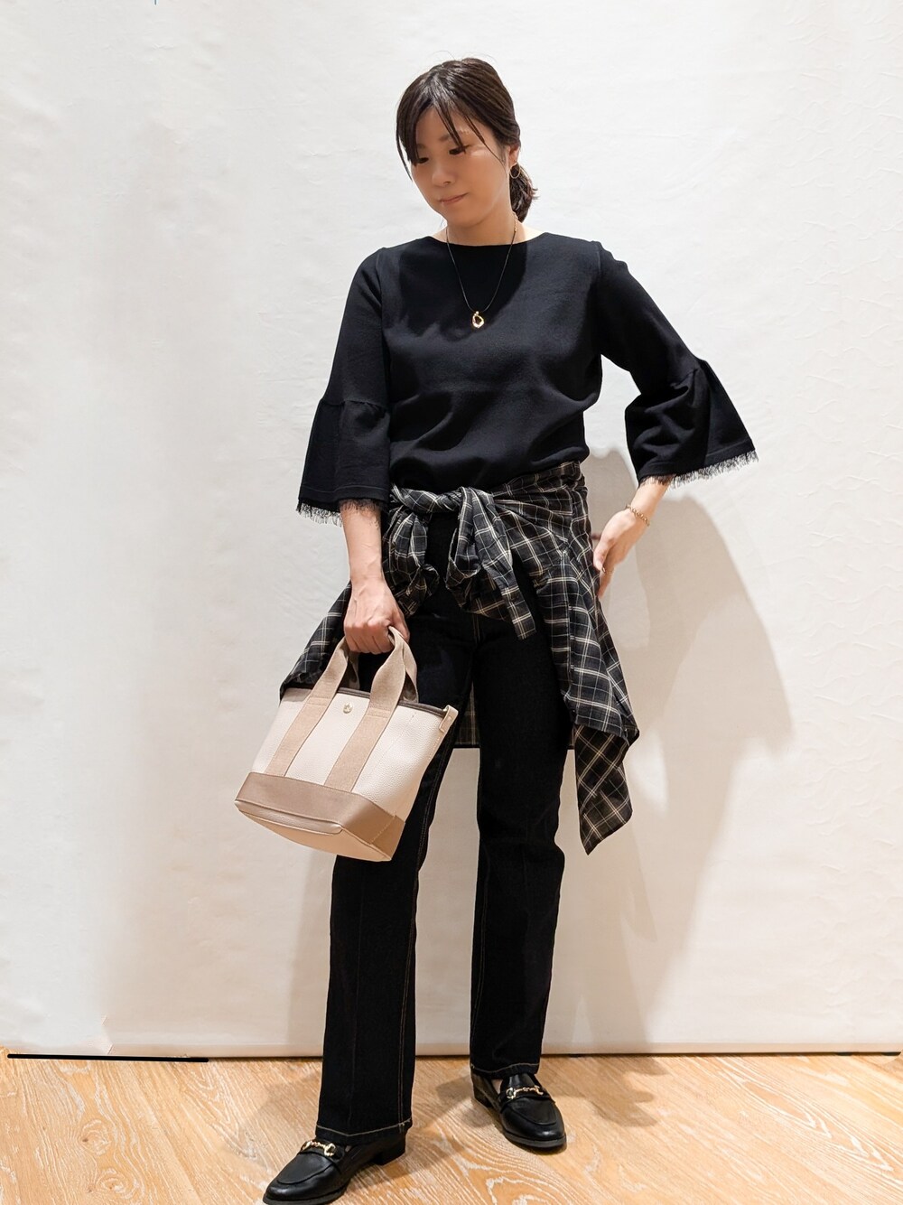 グレー系のシャツ/ブラウス、ブラック系のニット/セーター、ブルー系のデニムパンツを着用したレディースの秋コーディネートの2枚目の写真