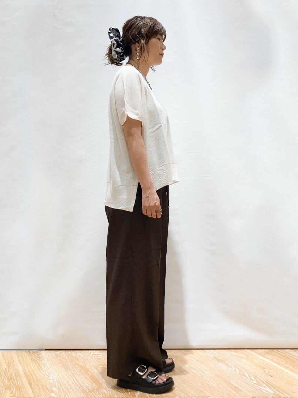 ホワイト系のニット/セーター、ブラウン系のその他パンツ、ブラック系のトートバッグを着用したレディースの夏コーディネートの4枚目の写真