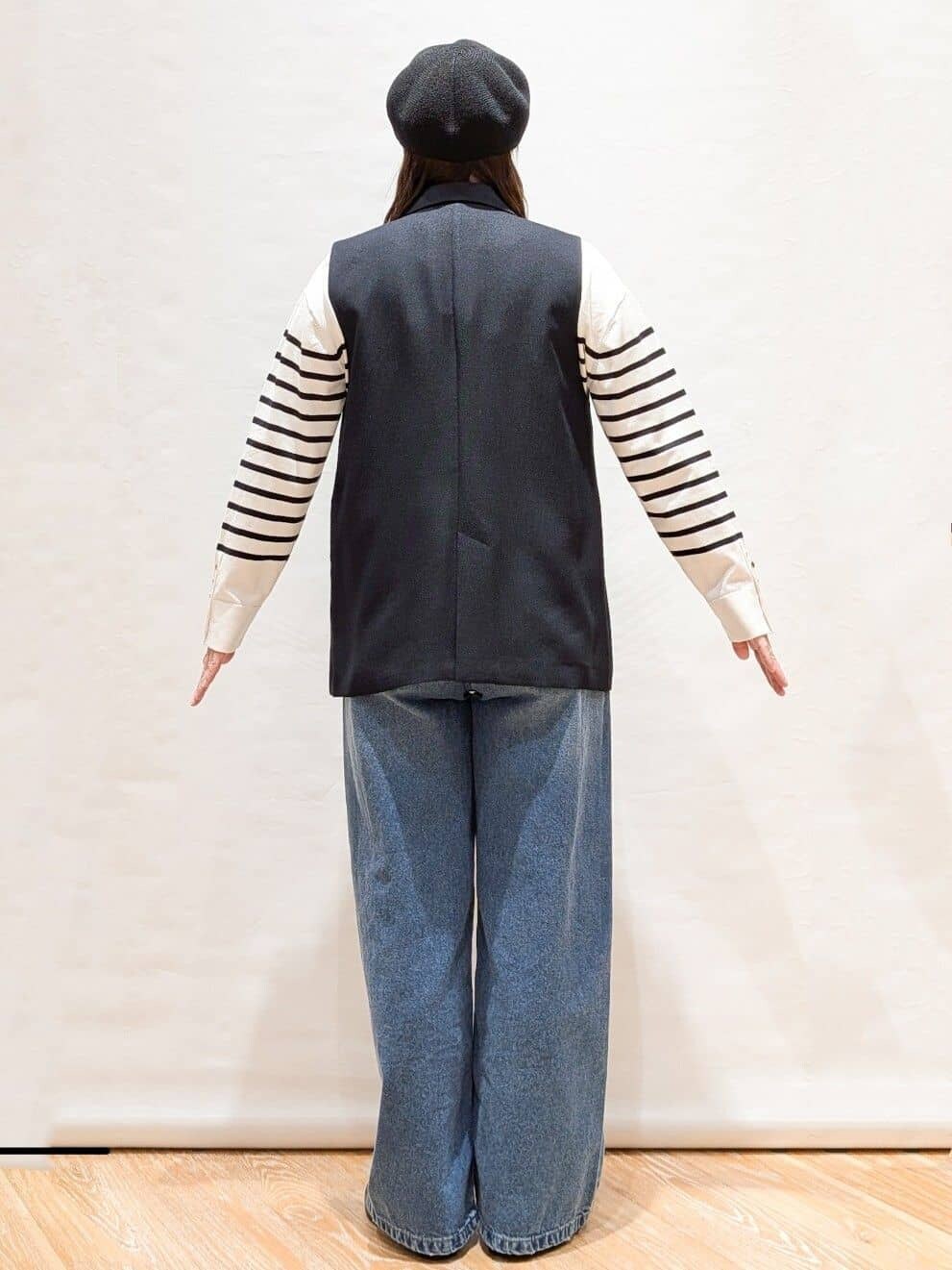 ブルー系のベスト、ホワイト系のニット/セーター、ブルー系のデニムパンツを着用したレディースの冬コーディネートの3枚目の写真