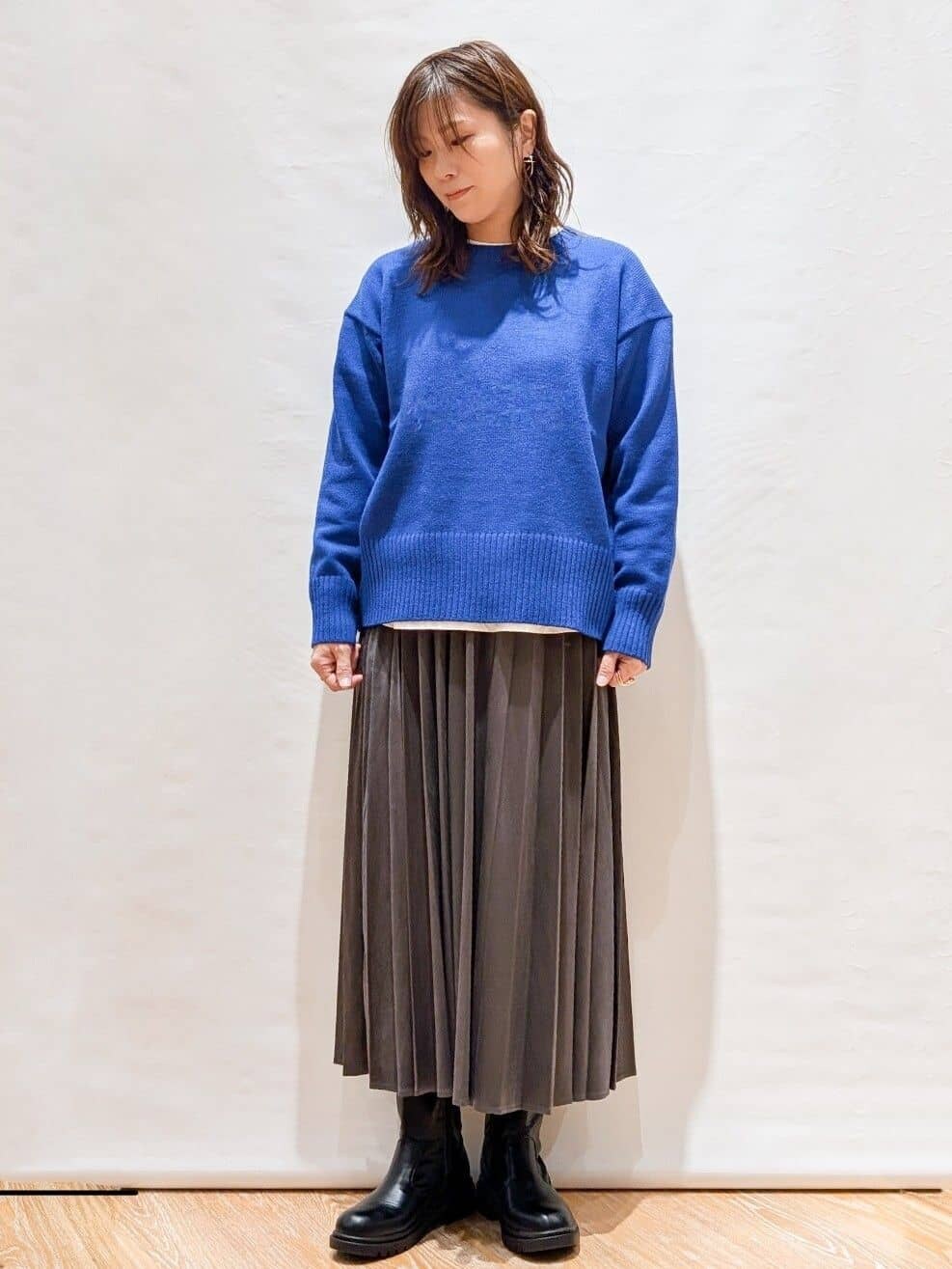 ホワイト系のTシャツ/カットソー、ブルー系のニット/セーター、グレー系のスカートを着用したレディースの秋コーディネートの3枚目の写真