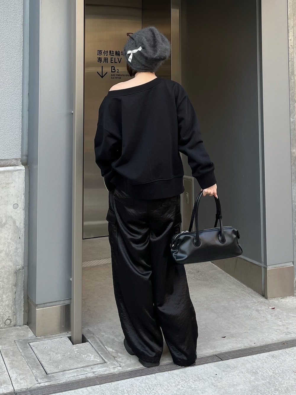 ブラック系のカーゴパンツ、ブラック系のトートバッグ、ブラック系のTシャツ/カットソーを着用したレディースの春コーディネートの2枚目の写真