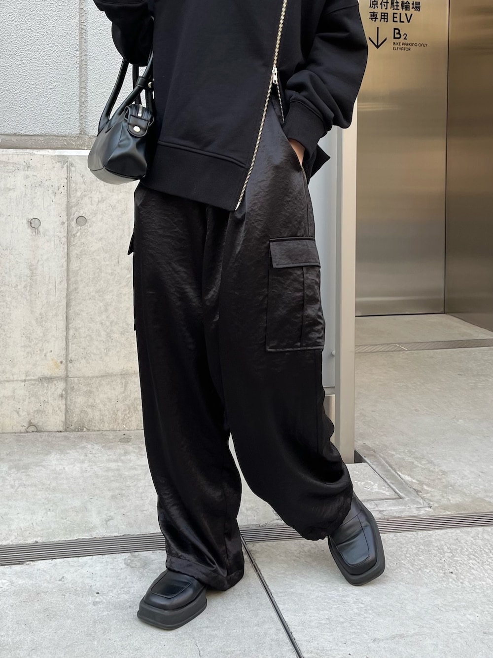 ブラック系のカーゴパンツ、ブラック系のトートバッグ、ブラック系のTシャツ/カットソーを着用したレディースの春コーディネートの4枚目の写真