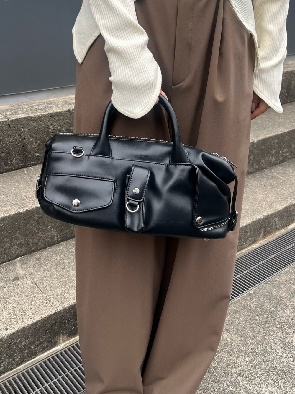 ブラウン系のスラックス、ホワイト系のTシャツ/カットソー、ブラック系のショルダーバッグを着用したレディースの春コーディネートの5枚目の写真