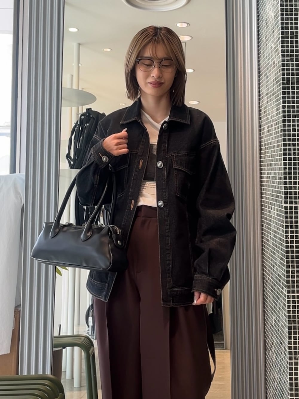 ブラウン系のスラックス、ブラック系のデニムジャケット、ホワイト系のTシャツ/カットソーを着用したレディースの春コーディネートの3枚目の写真