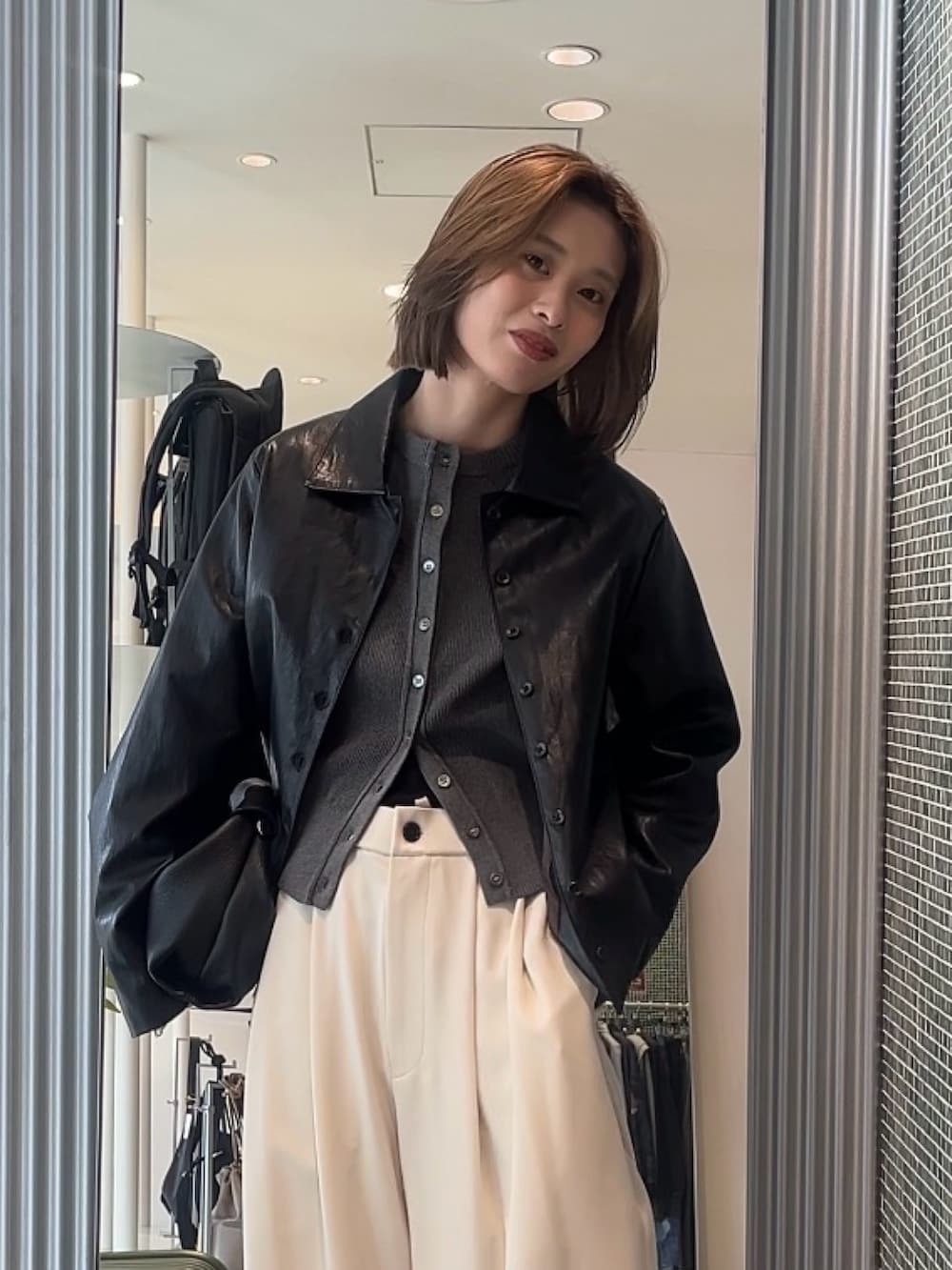 グレー系のスラックス、ブラック系のトートバッグ、グレー系のカーディガン/ボレロを着用したレディースの春コーディネートの3枚目の写真