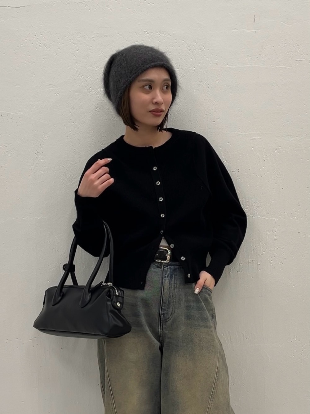 ブルー系のデニムパンツ、ブラック系のカーディガン/ボレロ、ブラック系のトートバッグを着用したレディースの春コーディネートの3枚目の写真