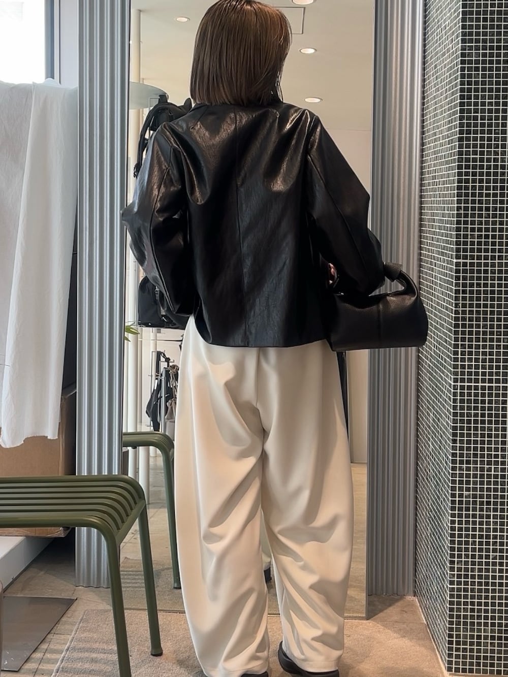 グレー系のスラックス、ブラック系のトートバッグ、グレー系のカーディガン/ボレロを着用したレディースの春コーディネートの2枚目の写真