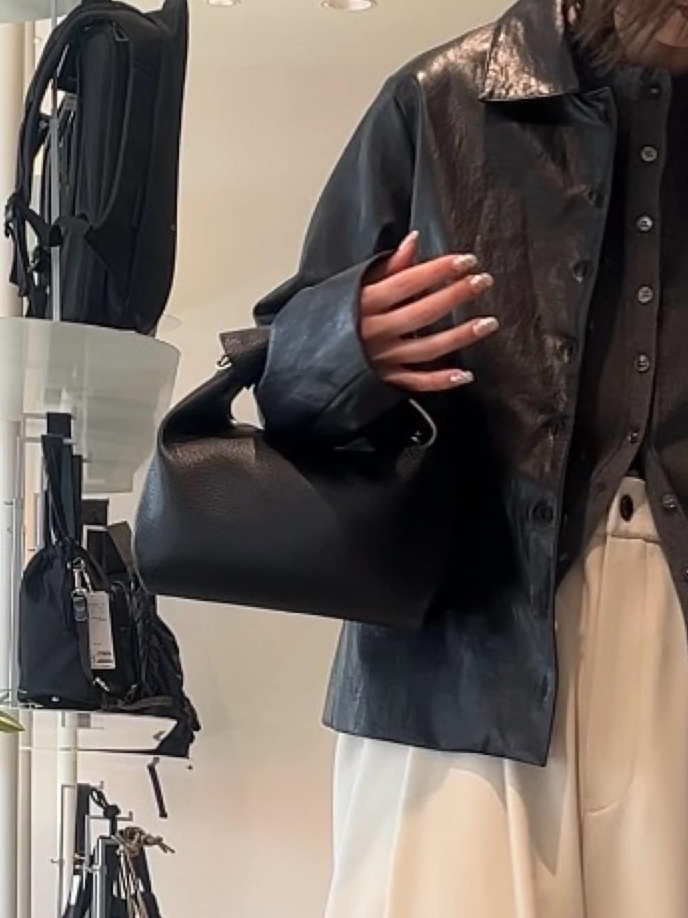 グレー系のスラックス、ブラック系のトートバッグ、グレー系のカーディガン/ボレロを着用したレディースの春コーディネートの5枚目の写真