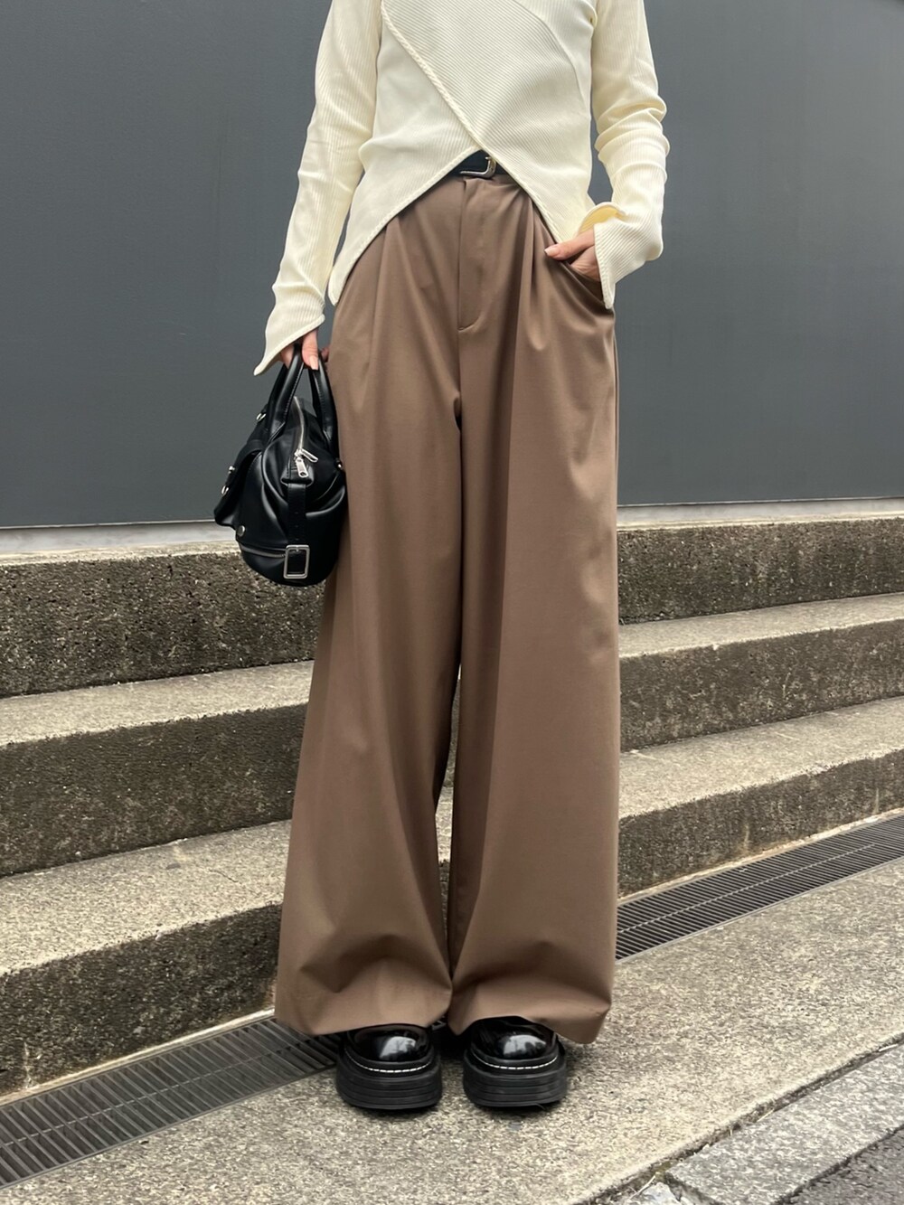 ブラウン系のスラックス、ホワイト系のTシャツ/カットソー、ブラック系のショルダーバッグを着用したレディースの春コーディネートの4枚目の写真