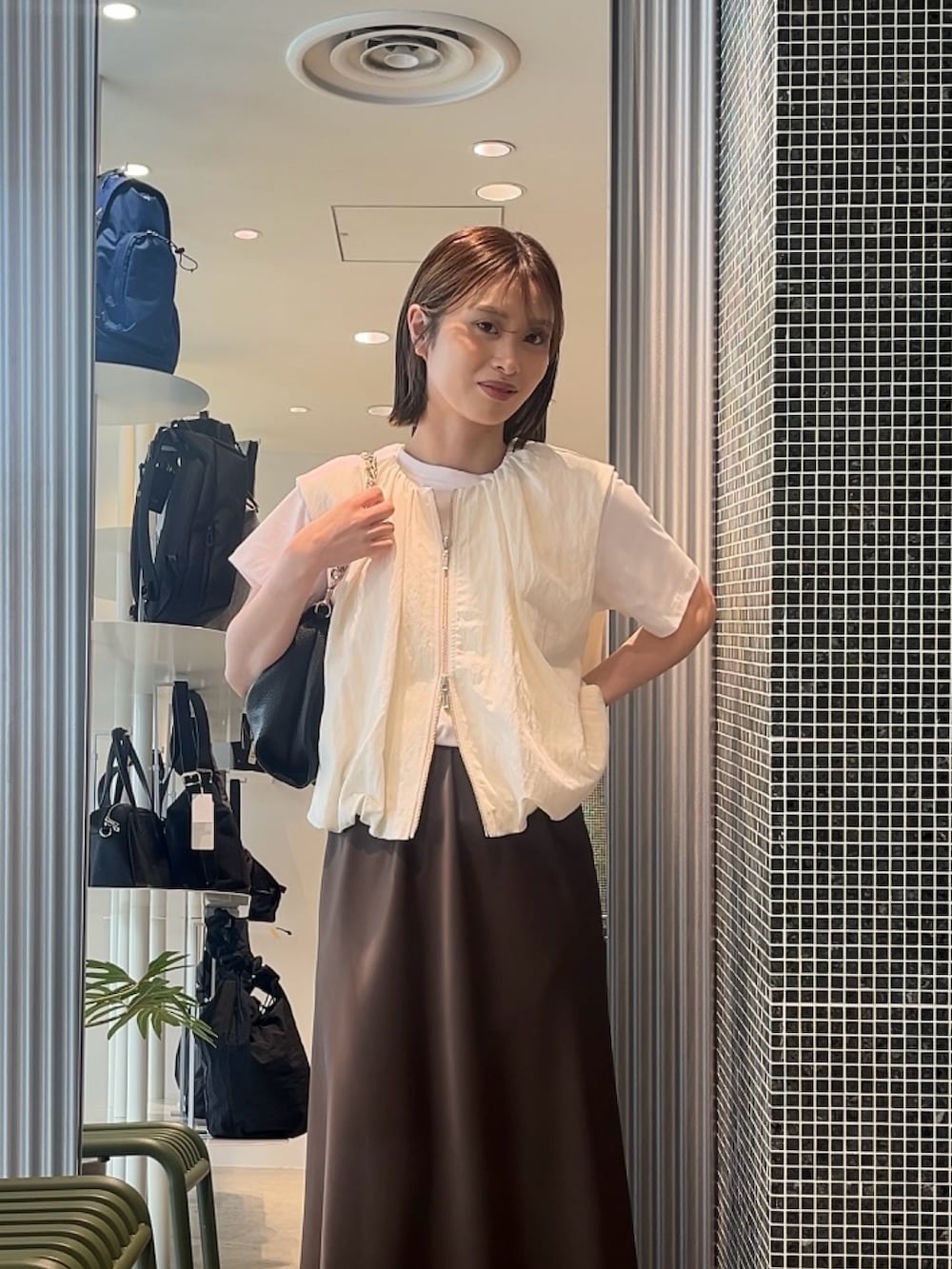 ホワイト系のベスト、ホワイト系のTシャツ/カットソー、ブラック系のトートバッグを着用したレディースの春コーディネートの3枚目の写真