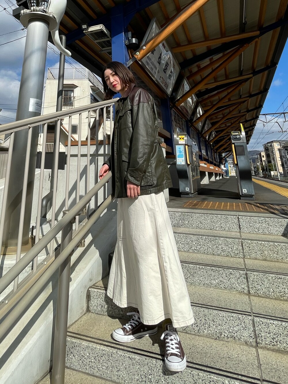 ブラウン系のスニーカー、ホワイト系のスカートを着用したレディースの秋コーディネートの2枚目の写真