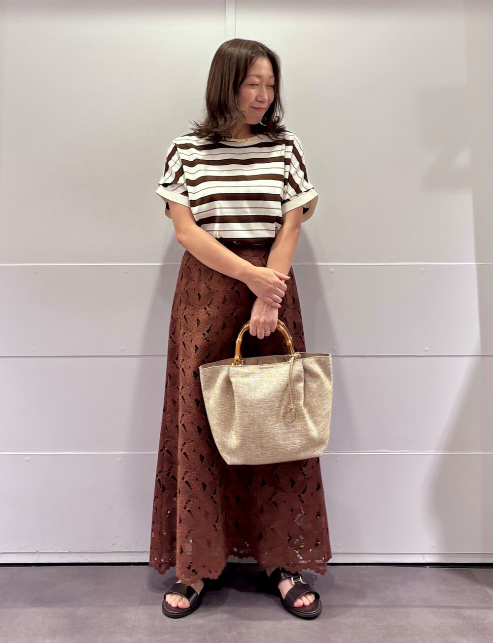 ベージュ系のニット/セーター、ブラウン系のスカート、ブラウン系のサンダルを着用したレディースの夏コーディネートの3枚目の写真