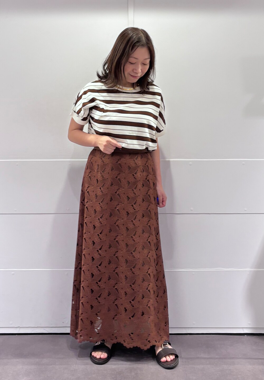 ベージュ系のニット/セーター、ブラウン系のスカート、ブラウン系のサンダルを着用したレディースの夏コーディネートの2枚目の写真