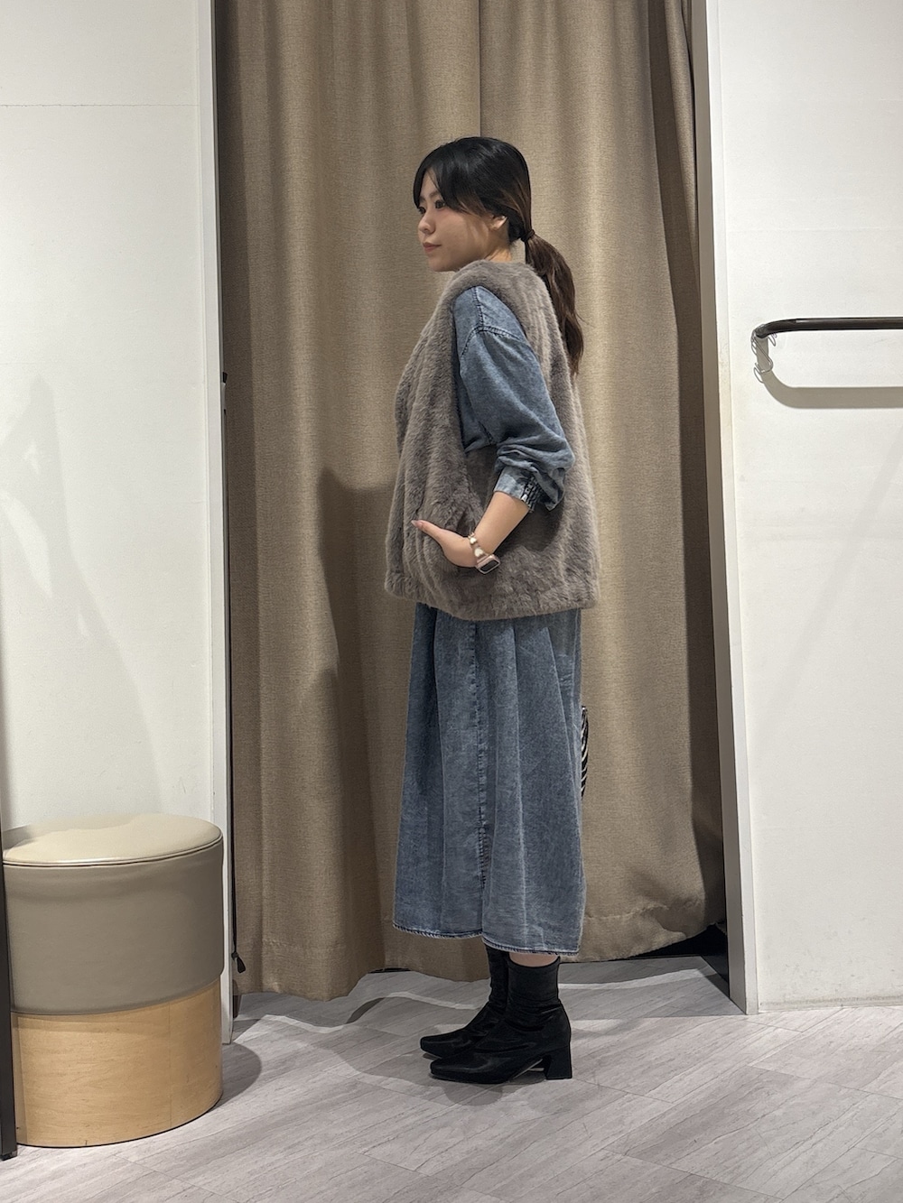 グレー系のベスト、ブルー系のワンピース、ブラック系のトートバッグを着用したレディースの秋コーディネートの2枚目の写真