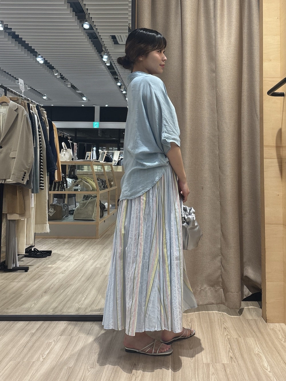 ブルー系のシャツ/ブラウス、ブルー系のスカート、ブラック系のトートバッグを着用したレディースの夏コーディネートの2枚目の写真