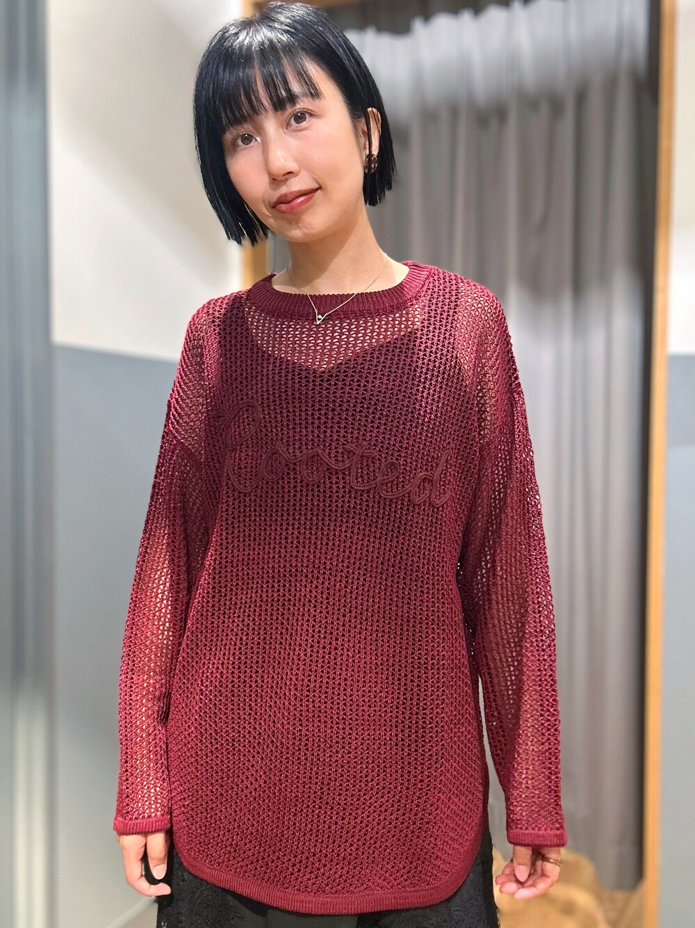レッド系のニット/セーター、ブラック系のタンクトップ、ブルー系のデニムパンツを着用したレディースの秋コーディネートの4枚目の写真