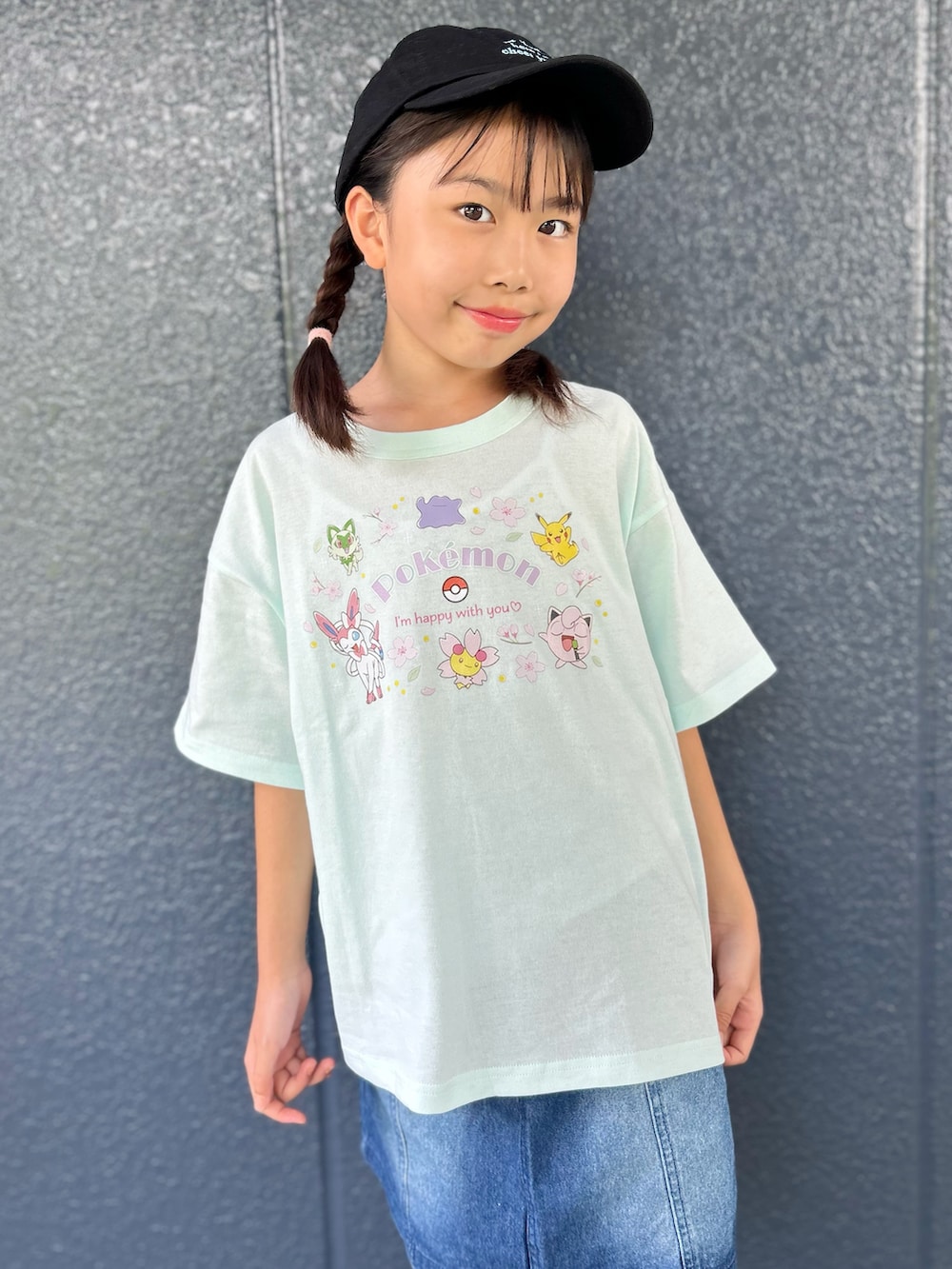 グリーン系のTシャツ/カットソー、ブルー系のデニムスカート、ブラック系のキャップを着用したキッズの夏コーディネートの4枚目の写真