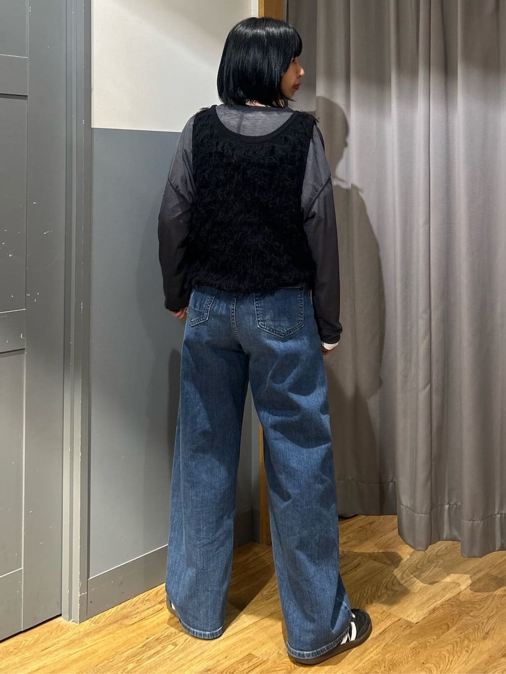 グレー系のTシャツ/カットソー、ブラック系のベスト、ブルー系のデニムパンツを着用したレディースの春コーディネートの3枚目の写真