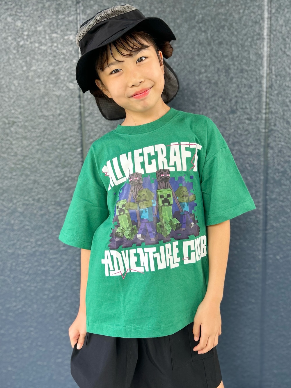 グリーン系のTシャツ/カットソー、ブラック系のスカート、ブラック系のハットを着用したキッズの夏コーディネートの4枚目の写真