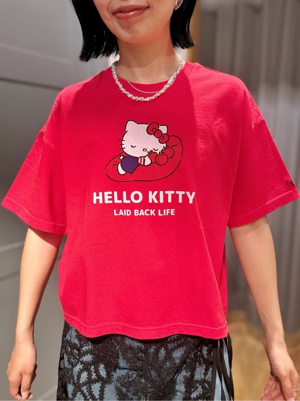 レッド系のTシャツ/カットソー、ブラック系のスカート、ブラック系のショルダーバッグを着用したレディースの春コーディネートの5枚目の写真