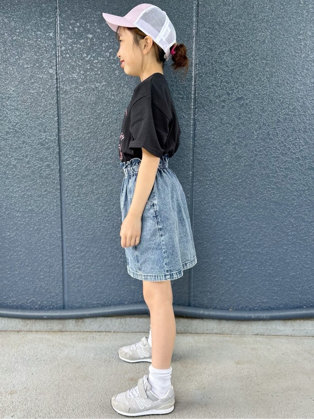 ブラック系のTシャツ/カットソー、ブルー系のデニムスカート、パープル系のキャップを着用したレディースの春コーディネートの2枚目の写真
