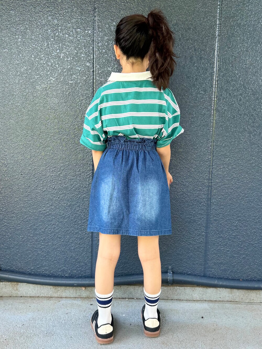グリーン系のTシャツ/カットソー、ブルー系のデニムスカート、ブラック系のショルダーバッグを着用したキッズの春コーディネートの4枚目の写真