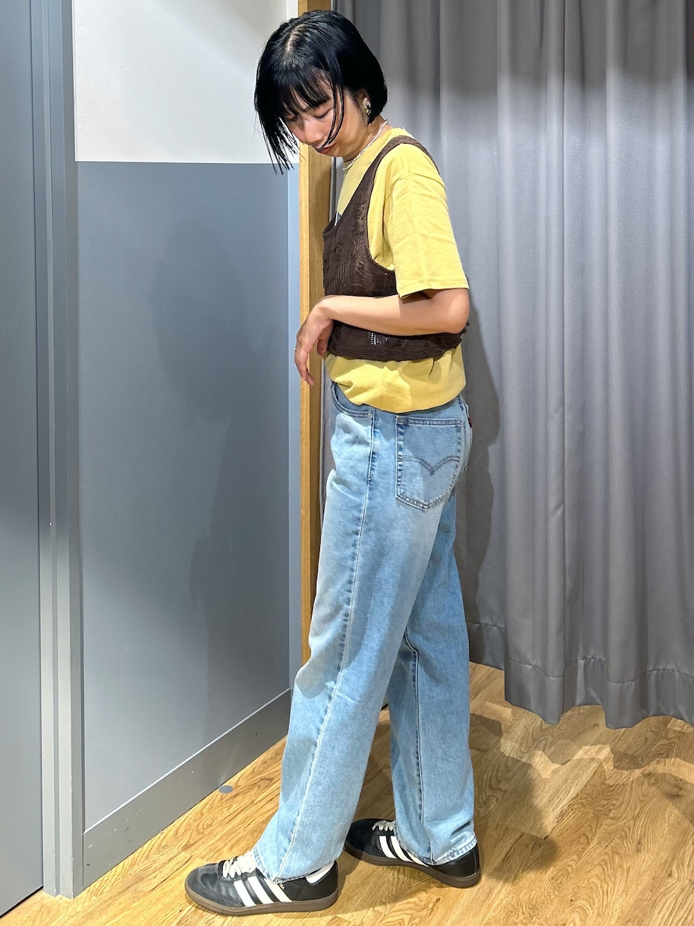 ブラウン系のベスト、ブルー系のデニムパンツ、ベージュ系のトートバッグを着用したレディースの夏コーディネートの3枚目の写真
