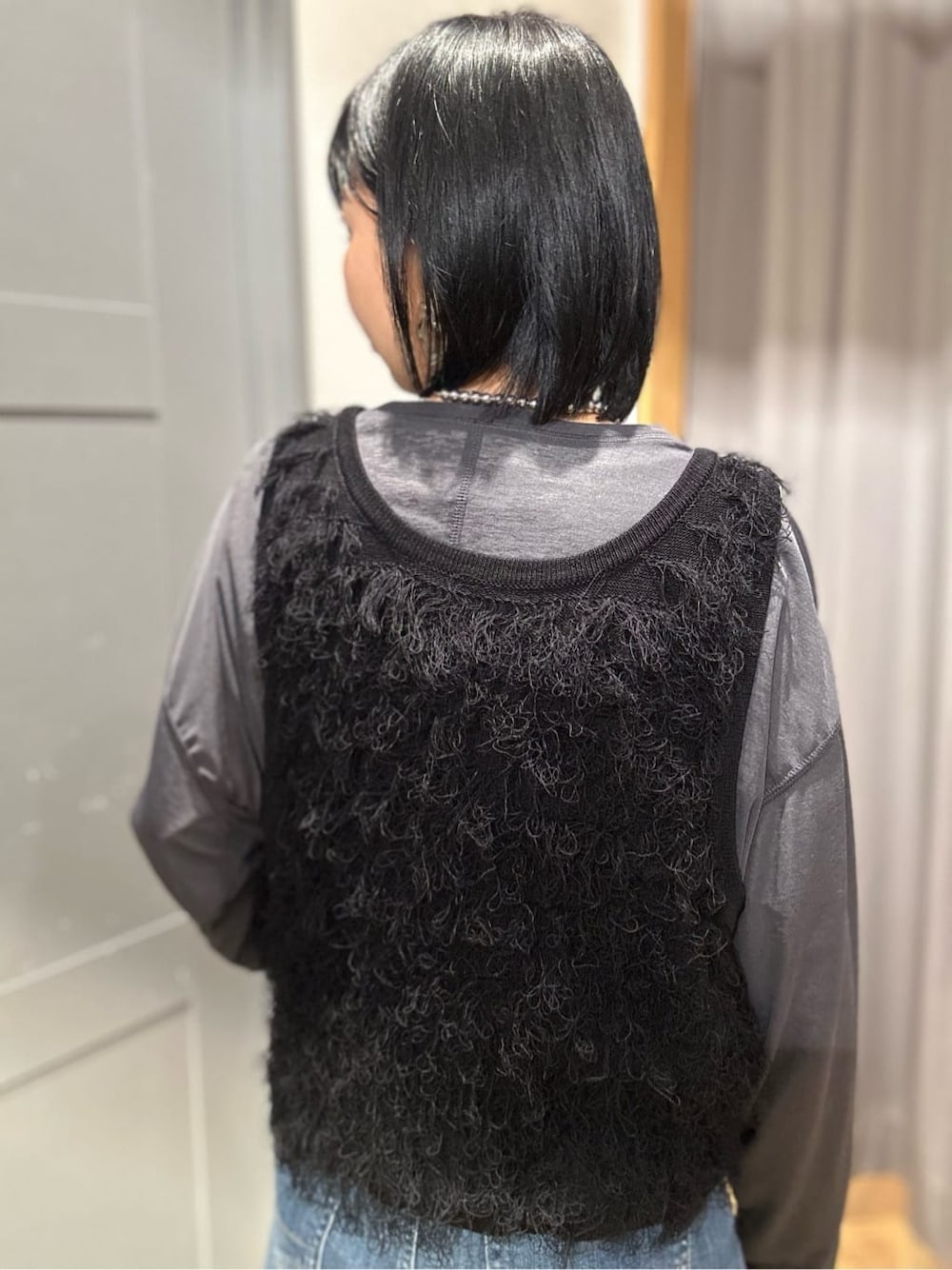グレー系のTシャツ/カットソー、ブラック系のベスト、ブルー系のデニムパンツを着用したレディースの春コーディネートの6枚目の写真