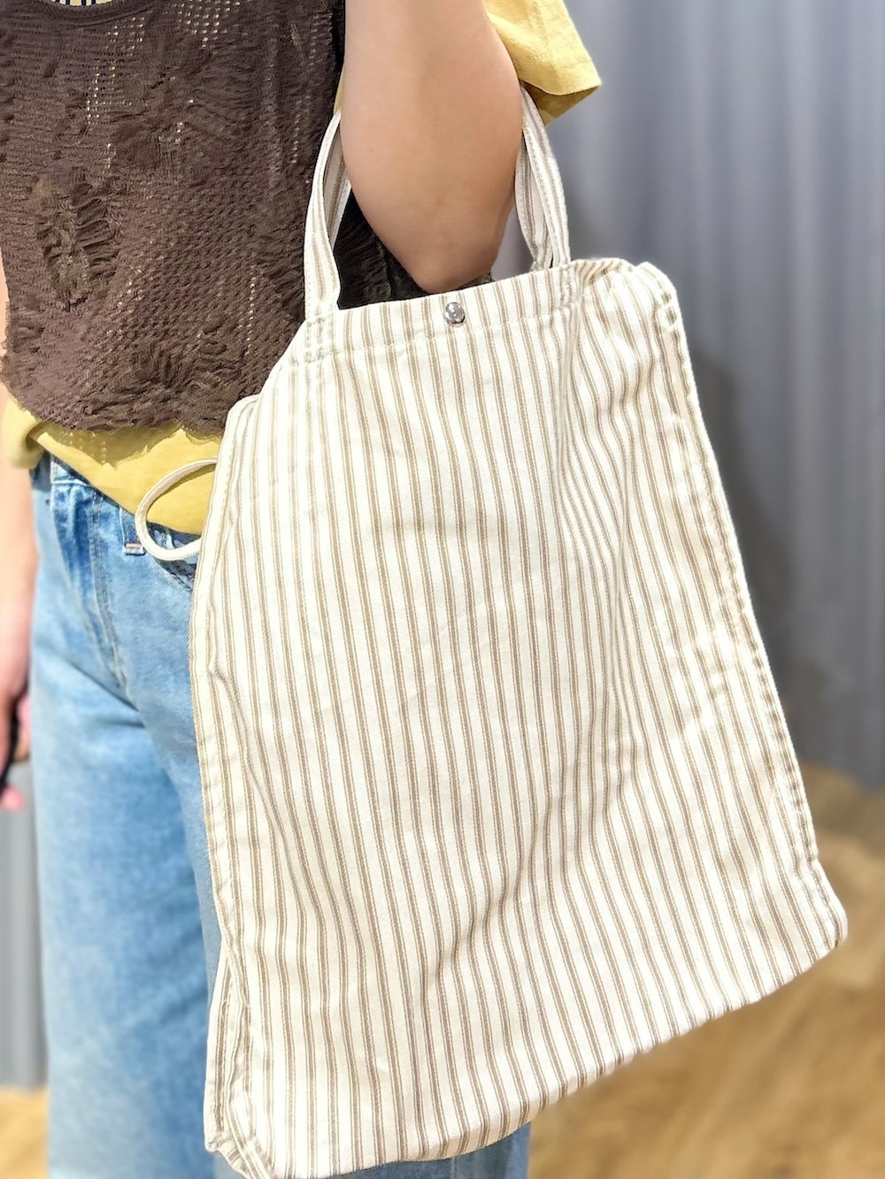ブラウン系のベスト、ブルー系のデニムパンツ、ベージュ系のトートバッグを着用したレディースの夏コーディネートの10枚目の写真