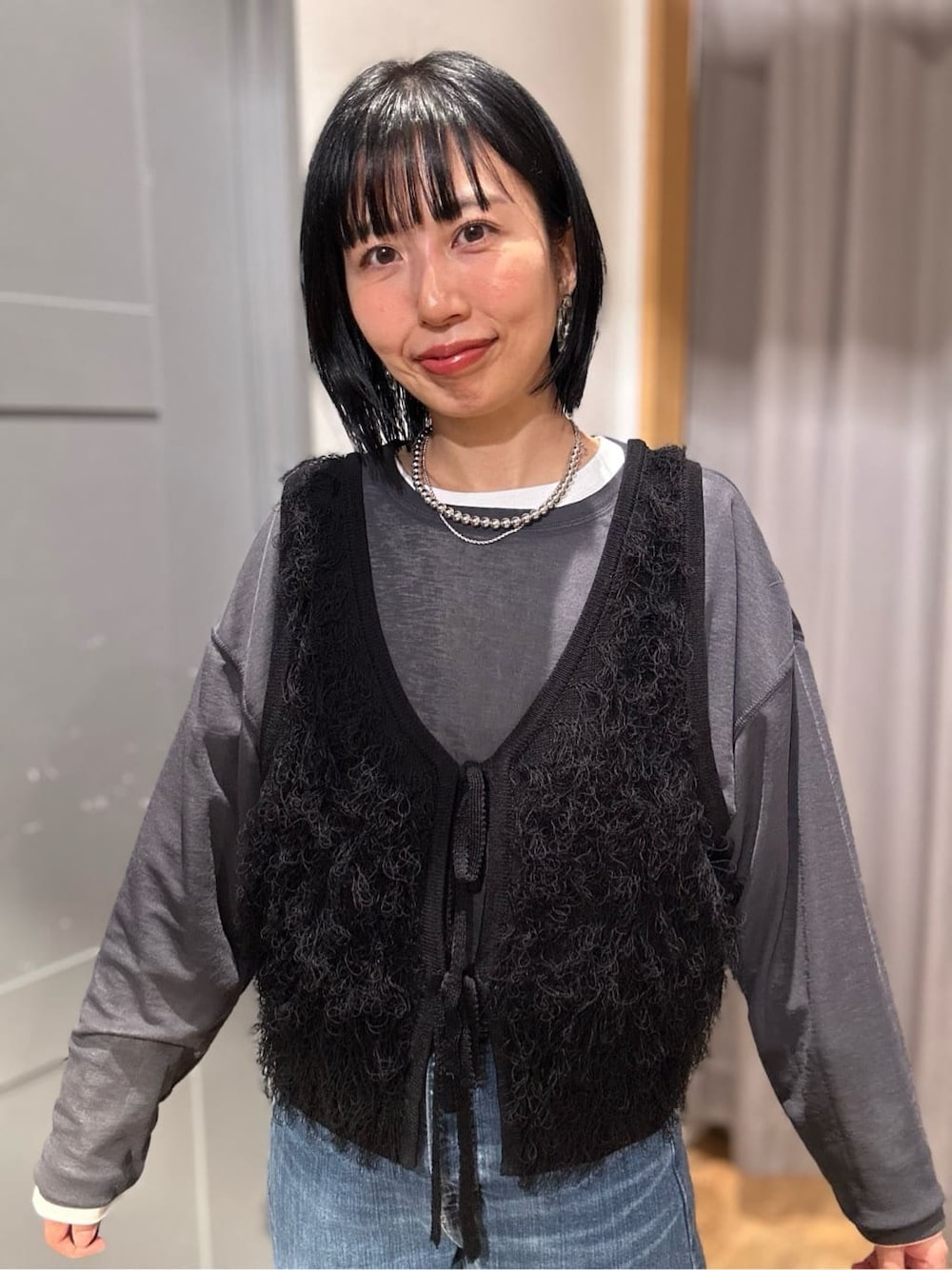グレー系のTシャツ/カットソー、ブラック系のベスト、ブルー系のデニムパンツを着用したレディースの春コーディネートの5枚目の写真