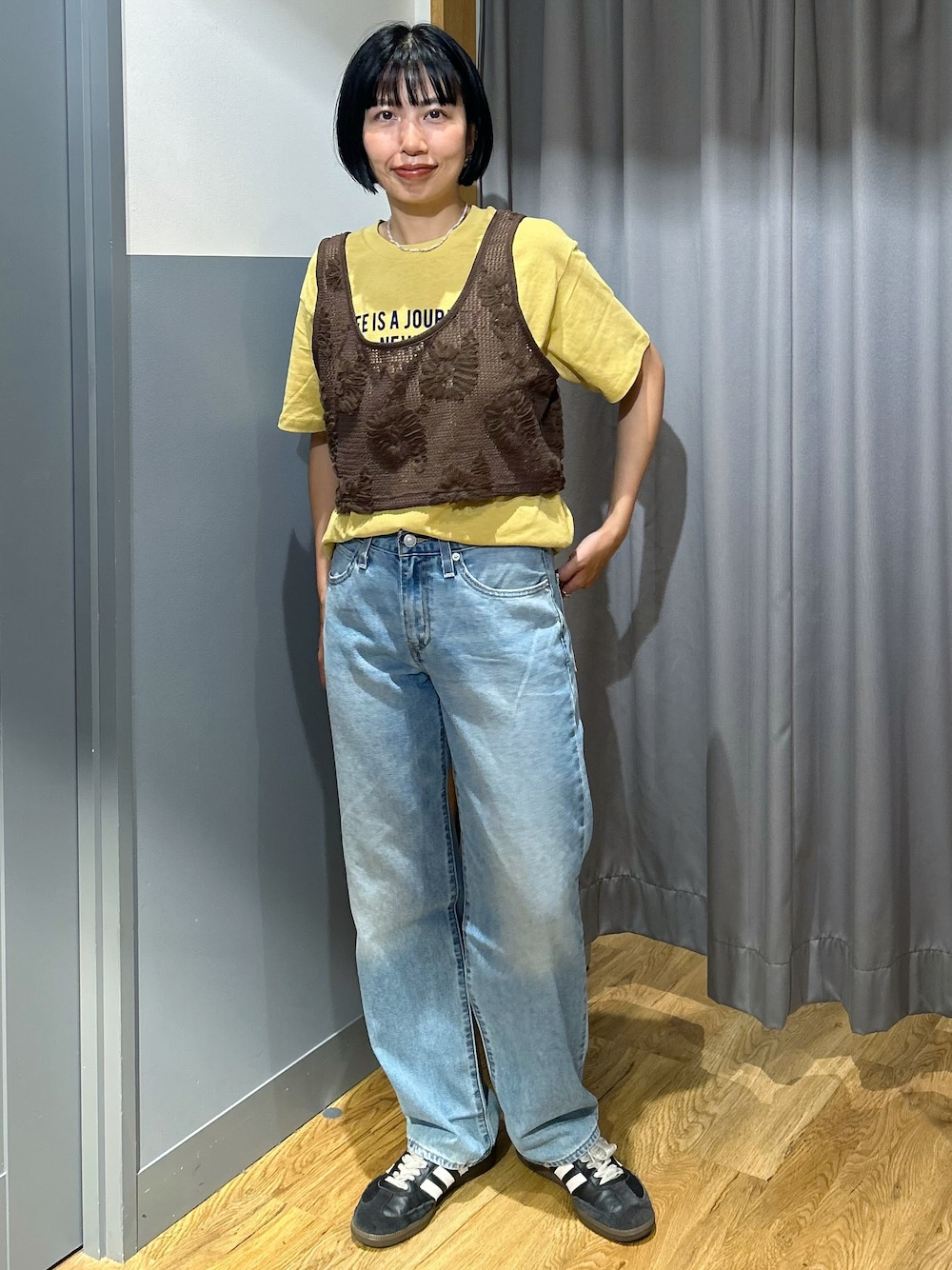 ブラウン系のベスト、ブルー系のデニムパンツ、ベージュ系のトートバッグを着用したレディースの夏コーディネートの2枚目の写真