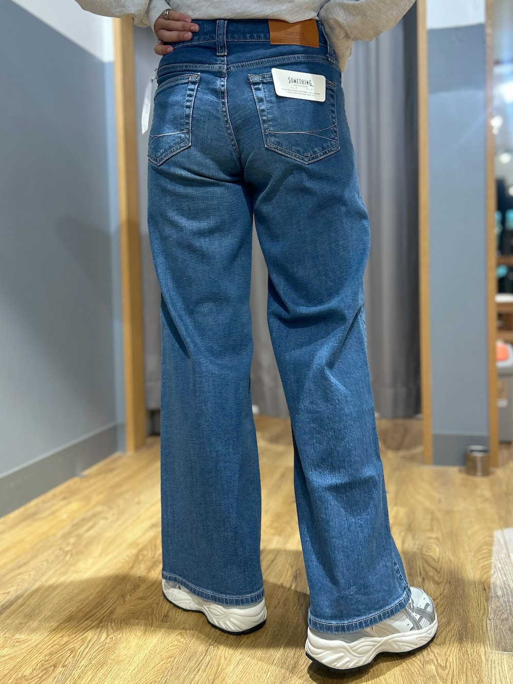グレー系のテーラードジャケット、グレー系のTシャツ/カットソー、ブルー系のデニムパンツを着用したレディースの秋コーディネートの7枚目の写真