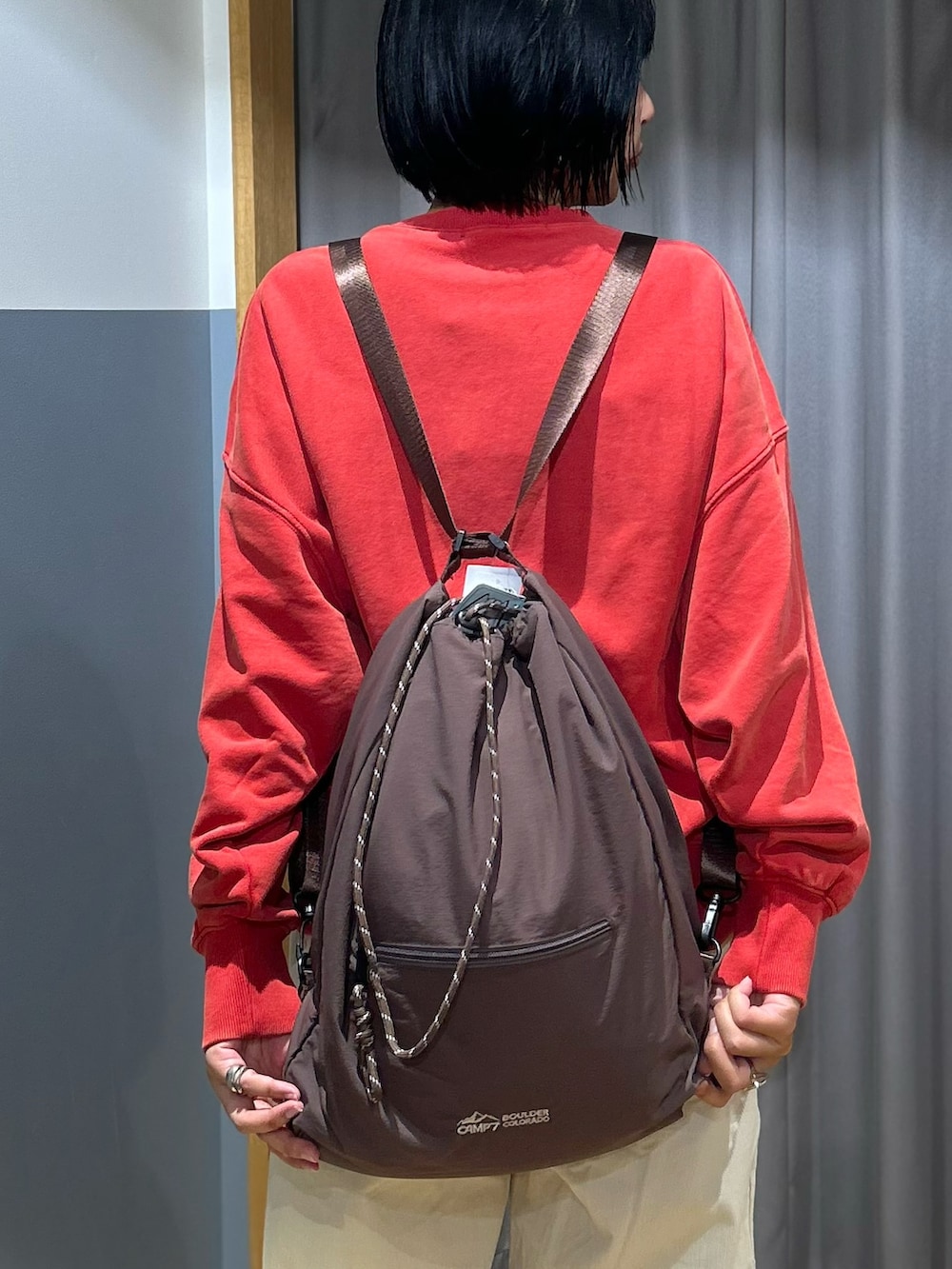 レッド系のスウェット、ホワイト系のその他パンツ、ブラウン系のバックパック/リュックを着用したレディースの秋コーディネートの8枚目の写真