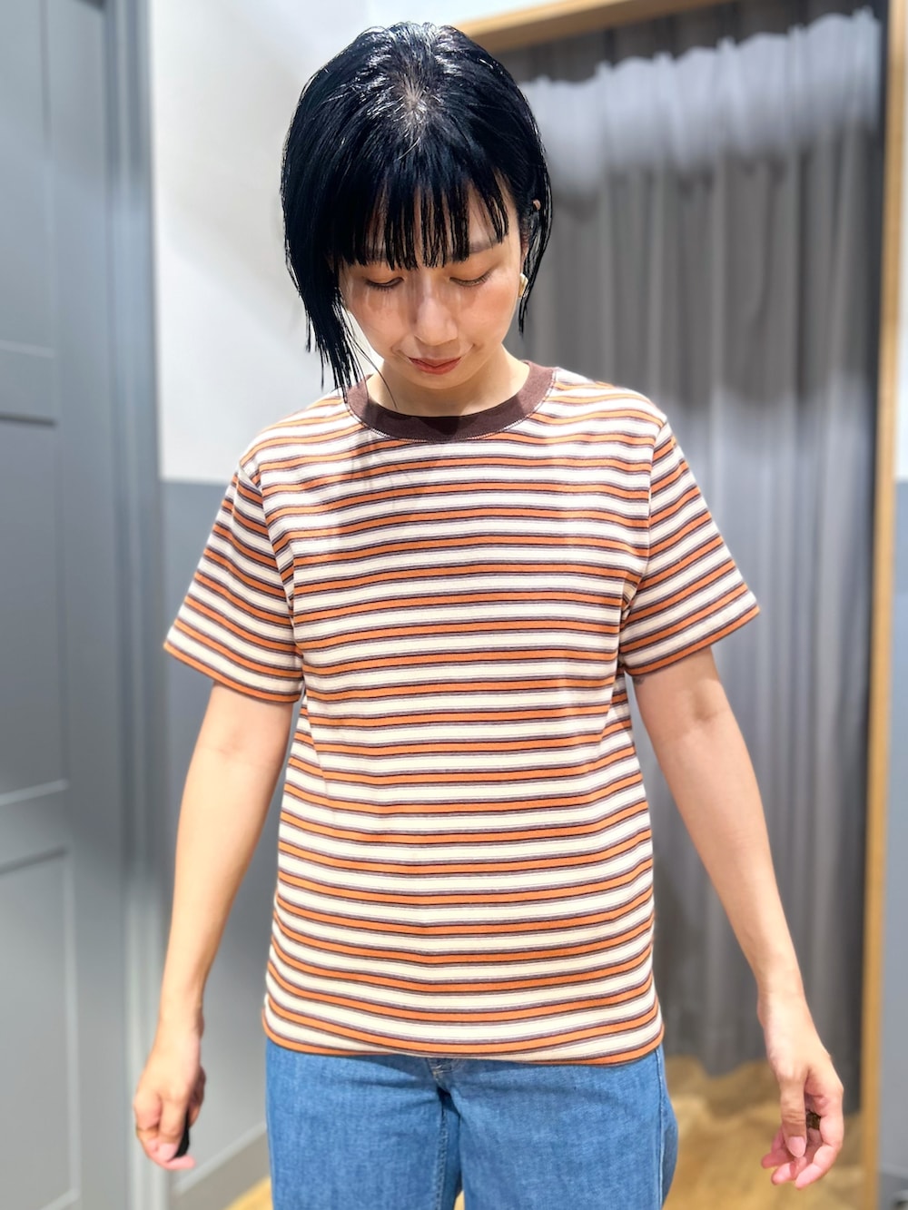 オレンジ系のTシャツ/カットソー、ブラウン系のテーラードジャケット、ブルー系のデニムパンツを着用したレディースの夏コーディネートの6枚目の写真