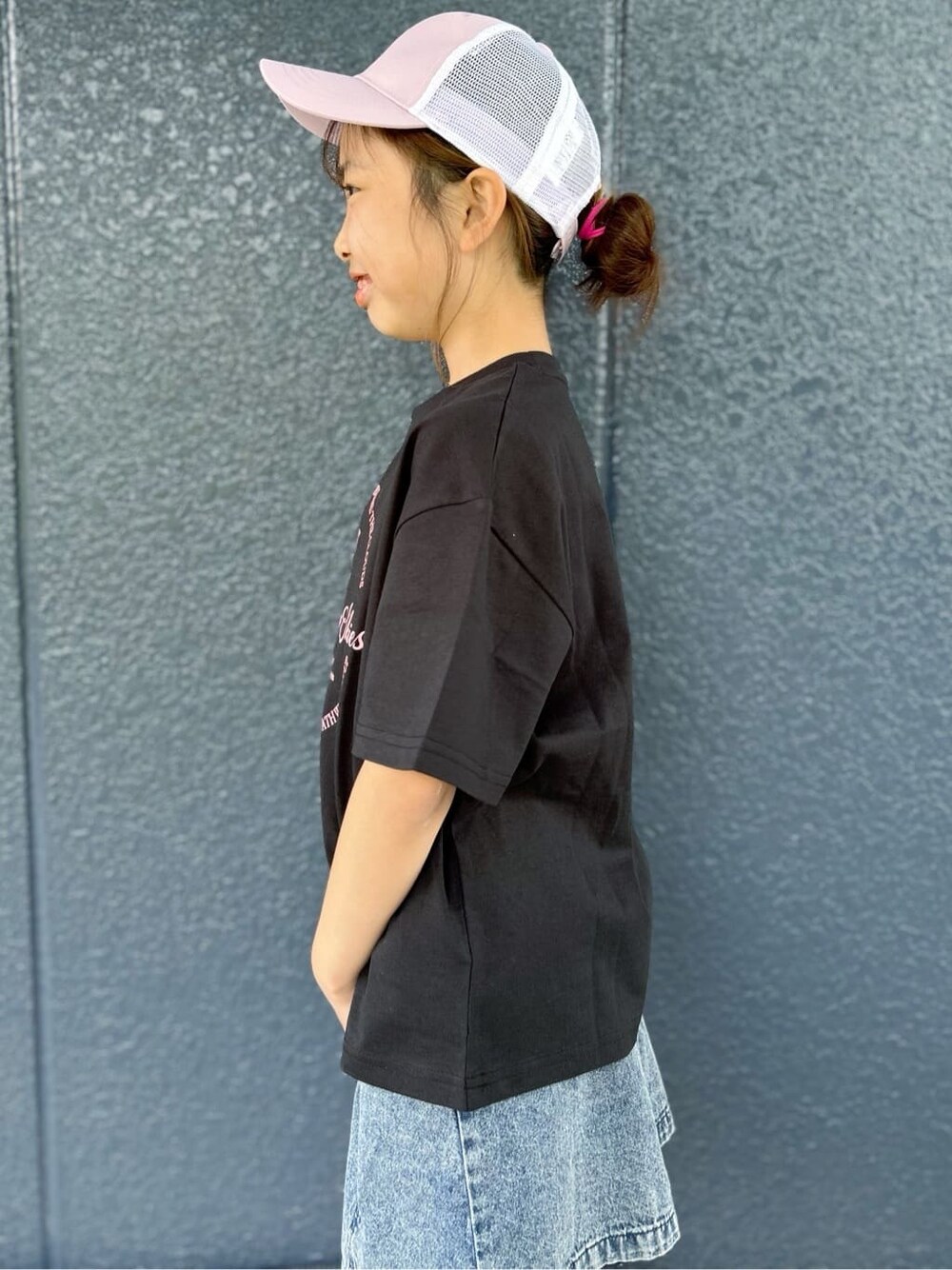 ブラック系のTシャツ/カットソー、ブルー系のデニムスカート、パープル系のキャップを着用したレディースの春コーディネートの5枚目の写真
