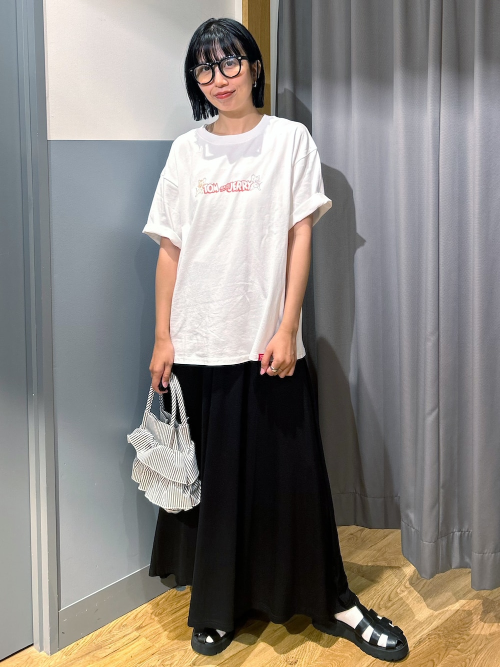 ホワイト系のTシャツ/カットソー、ブラック系のスカート、ホワイト系のショルダーバッグを着用したレディースの夏コーディネートの2枚目の写真