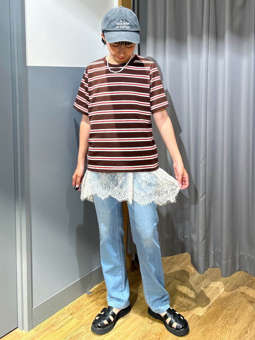 ブルー系のデニムパンツ、ブラック系のショルダーバッグ、ブラック系のキャップを着用したレディースの夏コーディネートの2枚目の写真