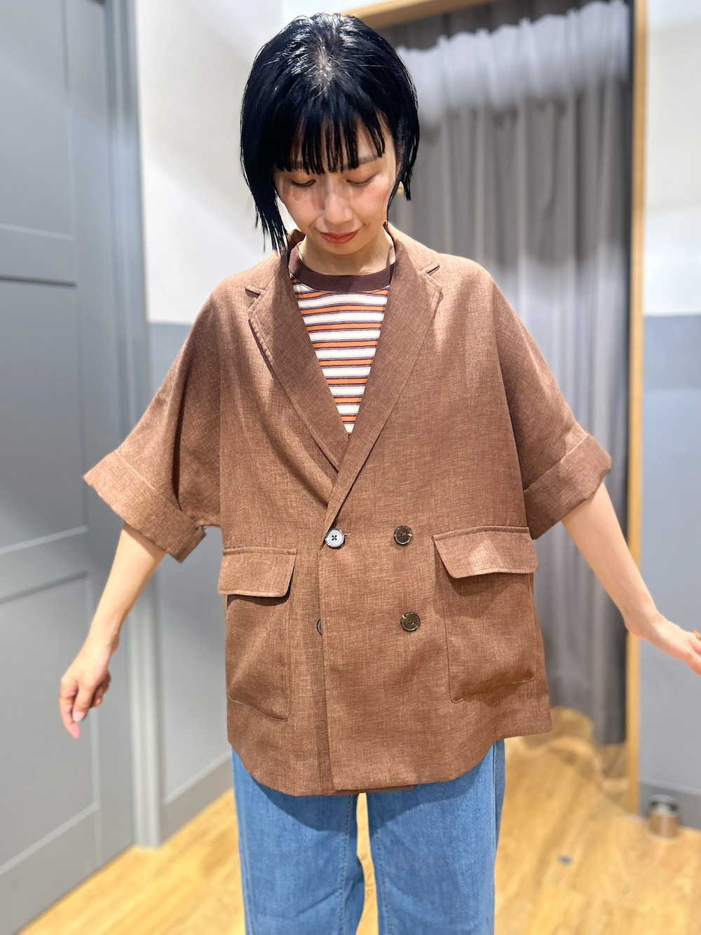 オレンジ系のTシャツ/カットソー、ブラウン系のテーラードジャケット、ブルー系のデニムパンツを着用したレディースの夏コーディネートの5枚目の写真
