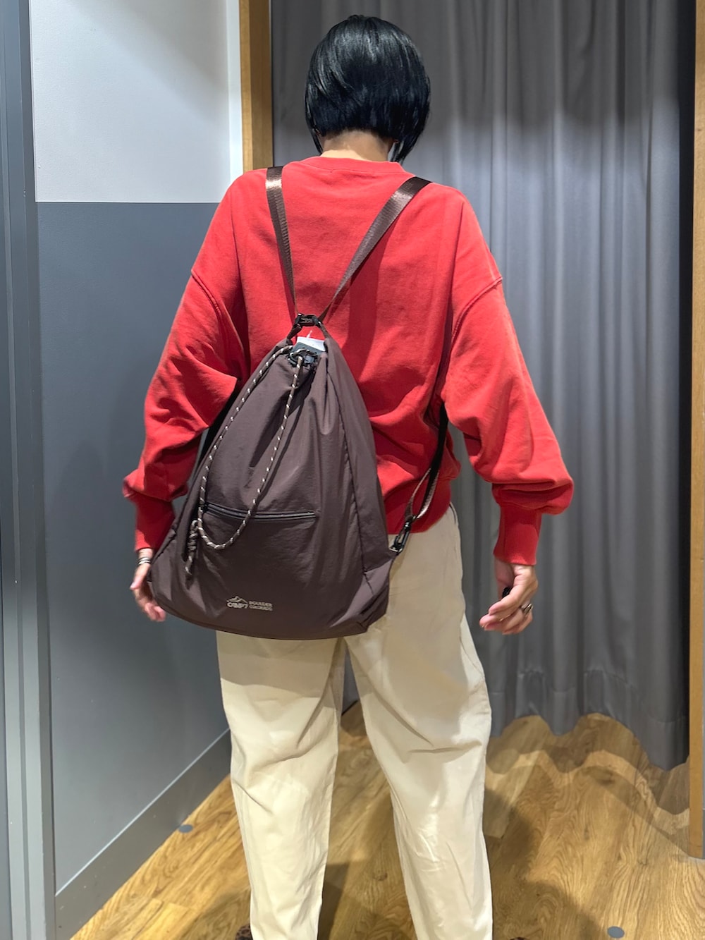 レッド系のスウェット、ホワイト系のその他パンツ、ブラウン系のバックパック/リュックを着用したレディースの秋コーディネートの3枚目の写真