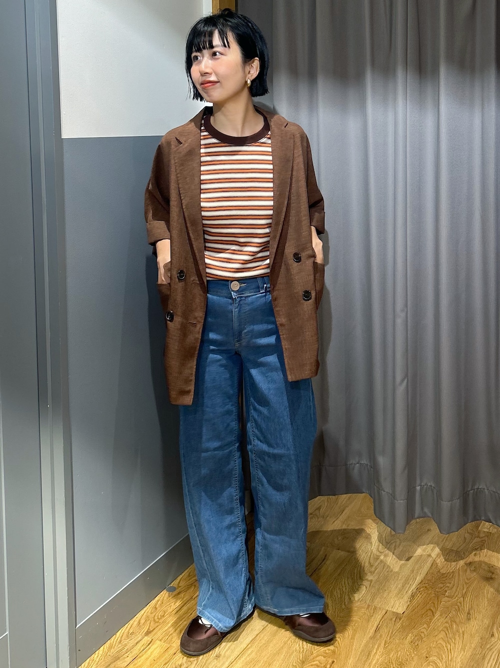 オレンジ系のTシャツ/カットソー、ブラウン系のテーラードジャケット、ブルー系のデニムパンツを着用したレディースの夏コーディネートの2枚目の写真