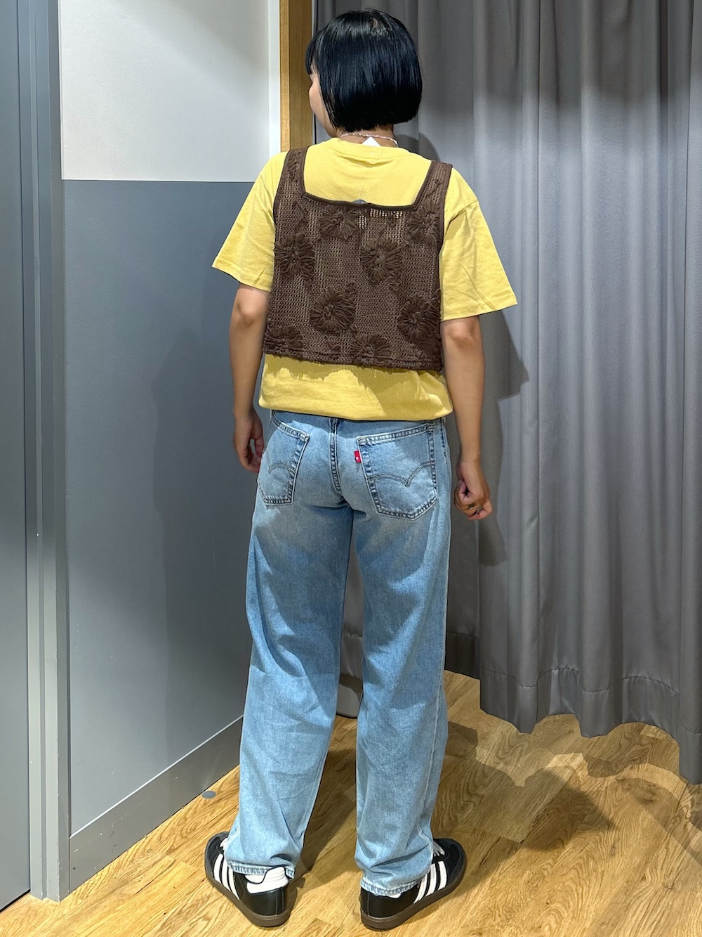 ブラウン系のベスト、ブルー系のデニムパンツ、ベージュ系のトートバッグを着用したレディースの夏コーディネートの4枚目の写真