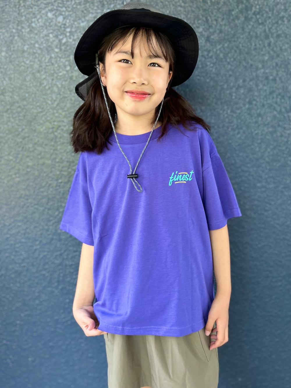 パープル系のTシャツ/カットソー、ブラウン系のスカート、ブラック系のハットを着用したキッズの春コーディネートの5枚目の写真
