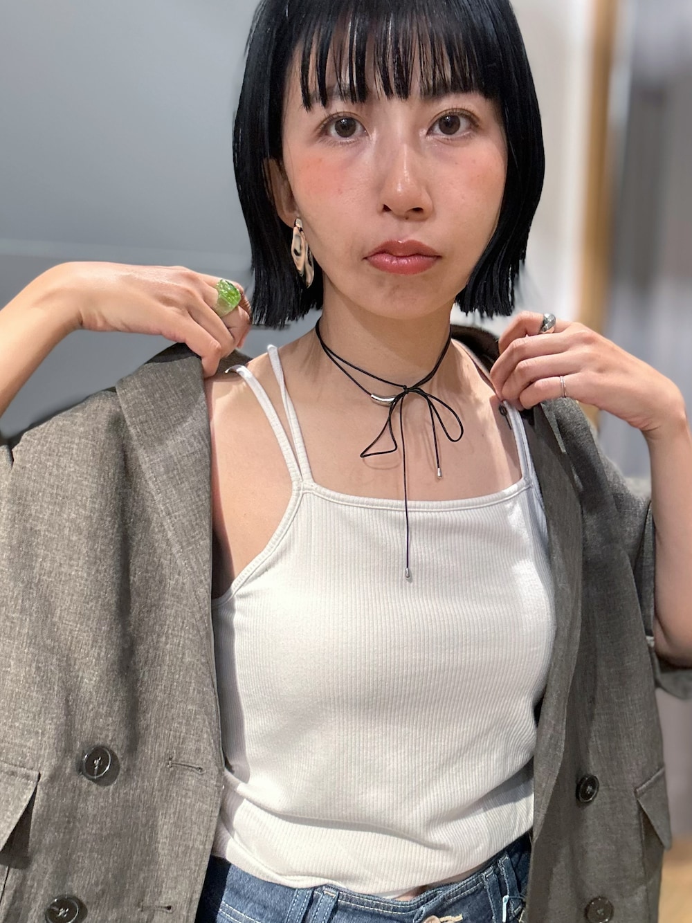 グレー系のテーラードジャケット、ホワイト系のタンクトップ、ブルー系のデニムパンツを着用したレディースの夏コーディネートの5枚目の写真