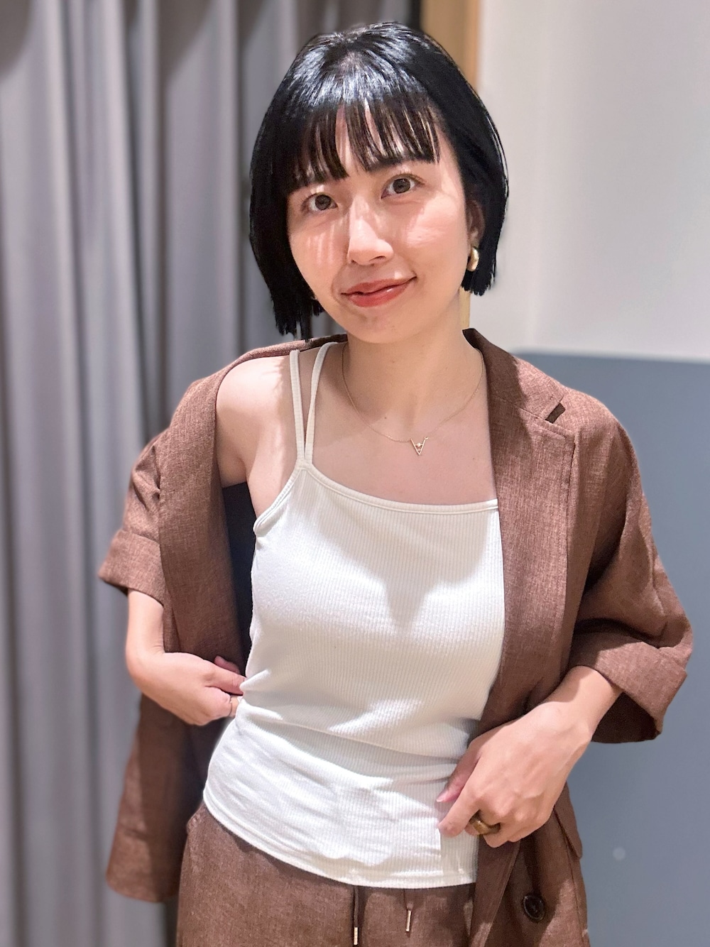 ブラウン系のテーラードジャケット、ブラウン系のその他パンツ、ホワイト系のタンクトップを着用したレディースの夏コーディネートの5枚目の写真