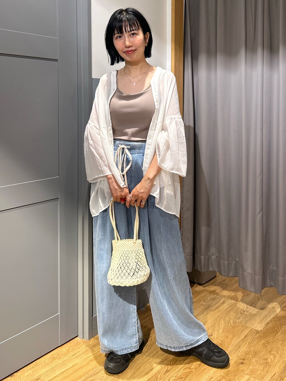 ベージュ系のタンクトップ、ホワイト系のシャツ/ブラウス、ブルー系のデニムパンツを着用したレディースの夏コーディネートの2枚目の写真