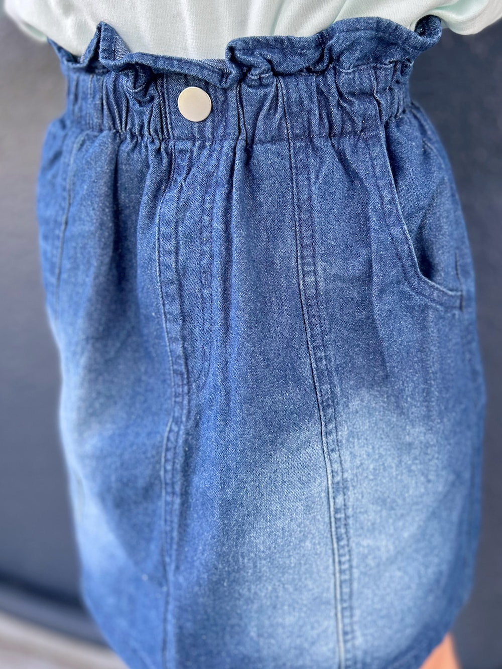 グリーン系のTシャツ/カットソー、ブルー系のデニムスカート、ブラック系のキャップを着用したキッズの夏コーディネートの8枚目の写真