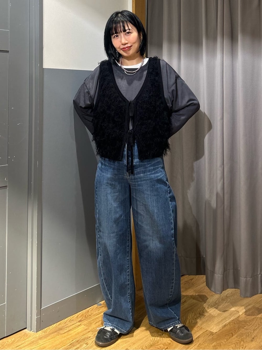 グレー系のTシャツ/カットソー、ブラック系のベスト、ブルー系のデニムパンツを着用したレディースの春コーディネートの2枚目の写真