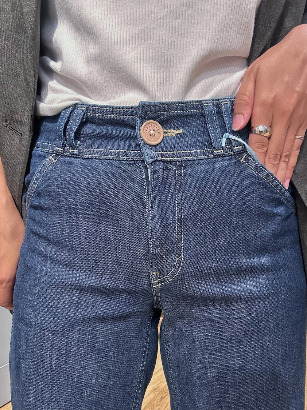 グレー系のテーラードジャケット、ホワイト系のタンクトップ、ブルー系のデニムパンツを着用したレディースの夏コーディネートの8枚目の写真